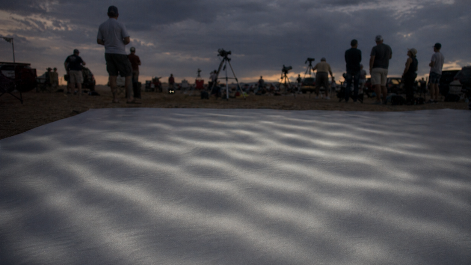 Faint shadow bands rippling across a white sheet before totality